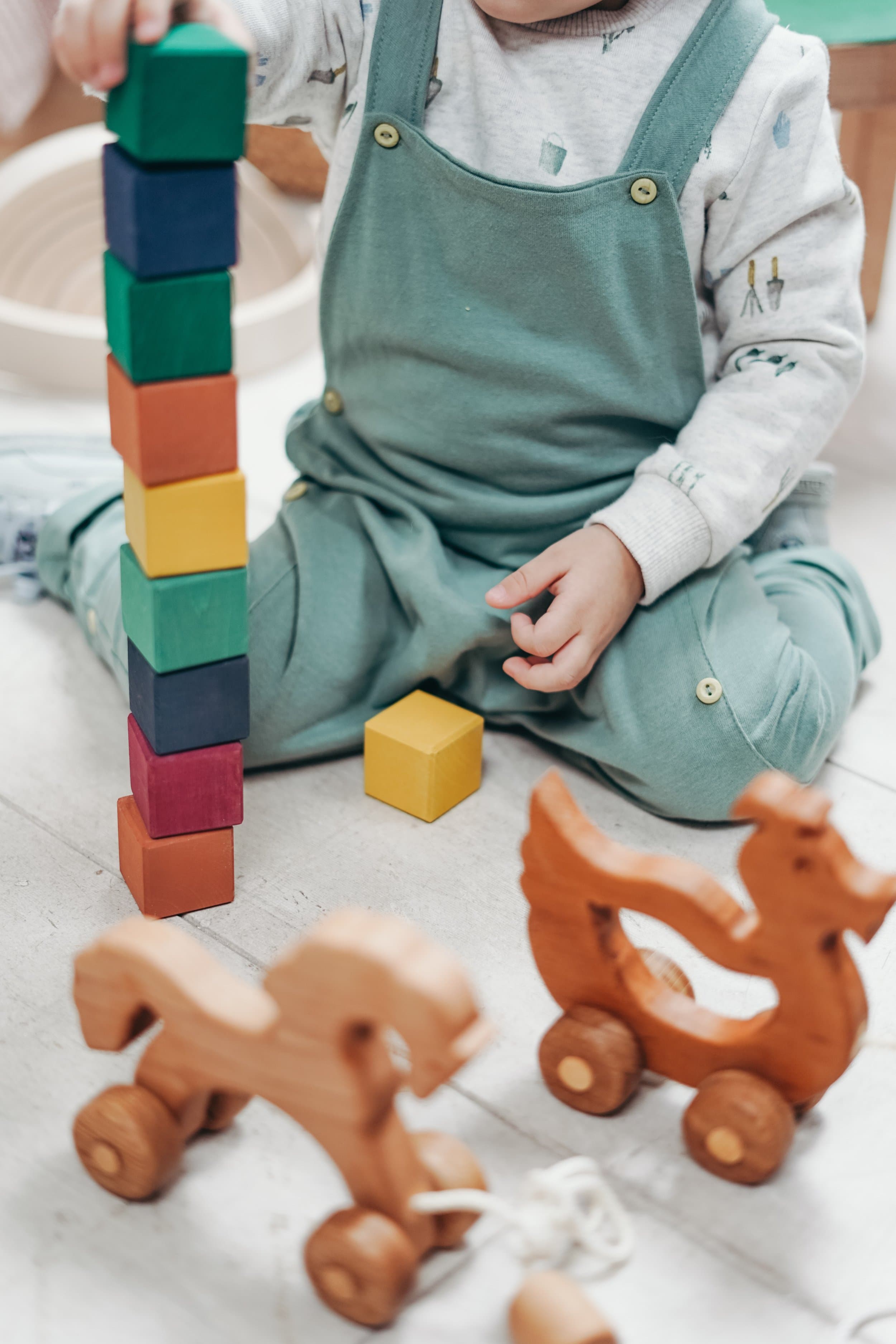 Child stacking colourful wooden blocks during a play-based learning activity designed to support communication and developmental skills.